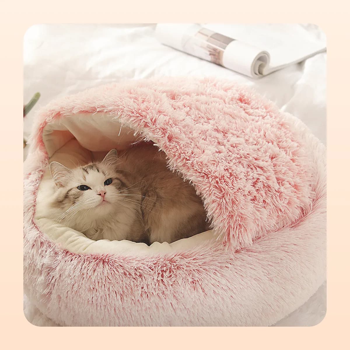 Kindral round plush burrow bed in pink with a cat inside