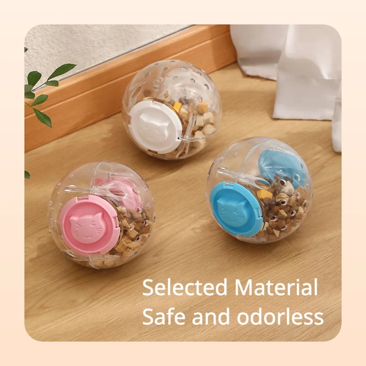 Three filled Kindral treat-dispensing balls on a wooden floor