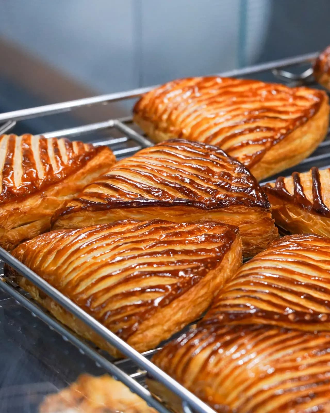 Golden puff pastry apple turnovers with glossy scored tops cooling on a wire rack